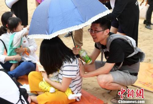 资料图:2017年5月,近200福州辣妈进行街头哺乳快闪活动,图为丈夫帮妻子撑伞。 吕明 摄